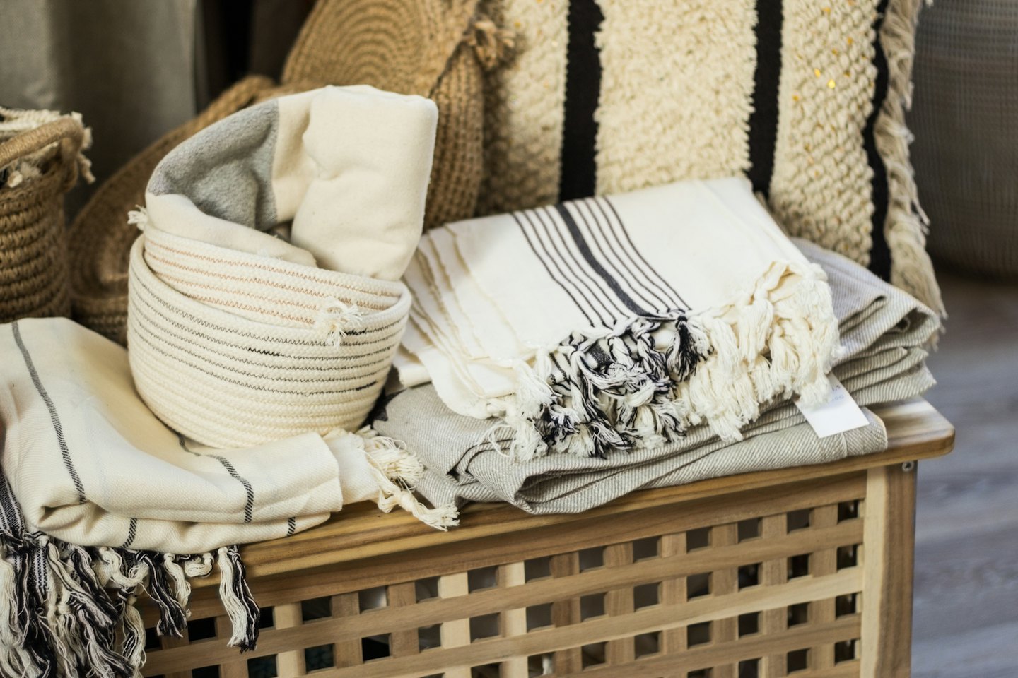 Neutral toned blankets and woven baskets on a wooden cabinet.